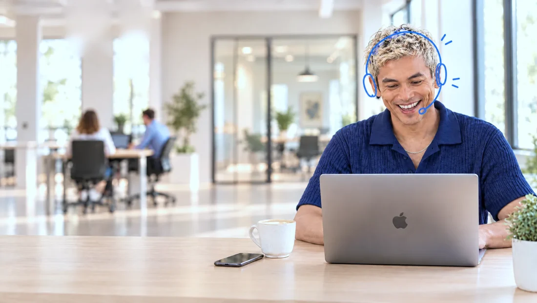 Lachende Credifin-medewerker met headset helpt een klant aan de telefoon terwijl hij het incassodossier op zijn MacBook verwerkt